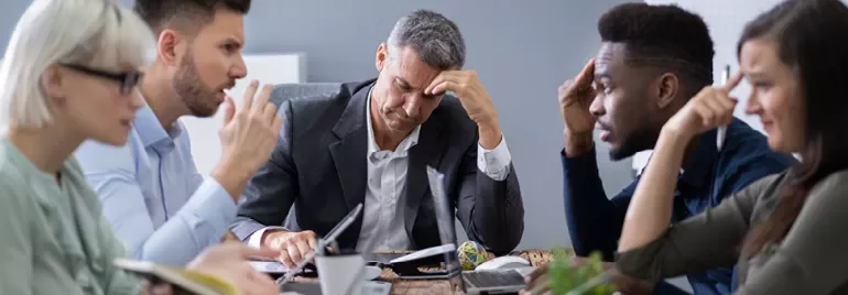 Réunion de travail avec des personnes réfléchissant à une table.