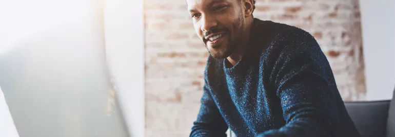 Personne souriante travaillant sur un ordinateur portable.
