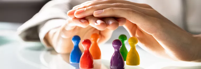 Mains couvrant des pions colorés sur une table.