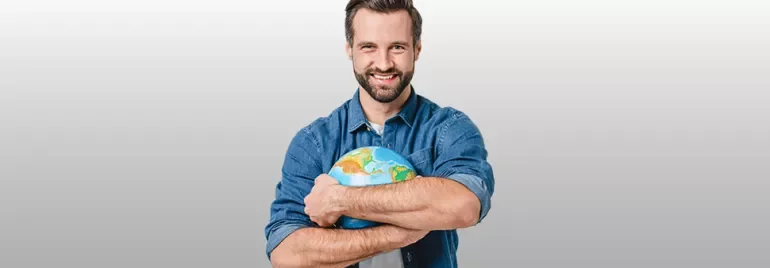 Personne tenant un globe terrestre avec un sourire.
