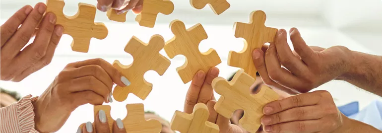 Des personnes tenant des pièces de puzzle en bois.