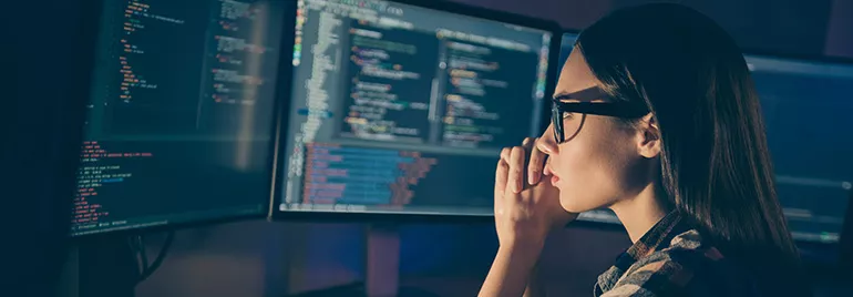 Personne travaillant sur des écrans avec du code informatique.