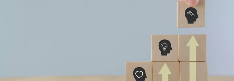 Blocs en bois avec icônes de têtes et flèches ascendantes.