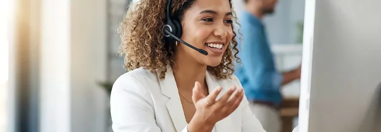 Conseiller(ère) client avec casque audio souriant(e) dans un centre de contact moderne.