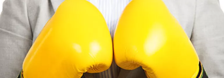 Personne en costume portant des gants de boxe jaunes.
