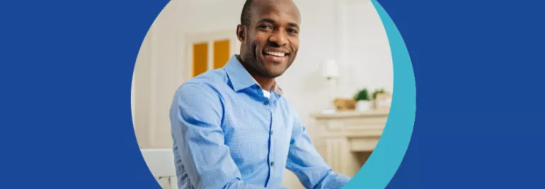 Personne souriante en chemise bleue, assise à une table.