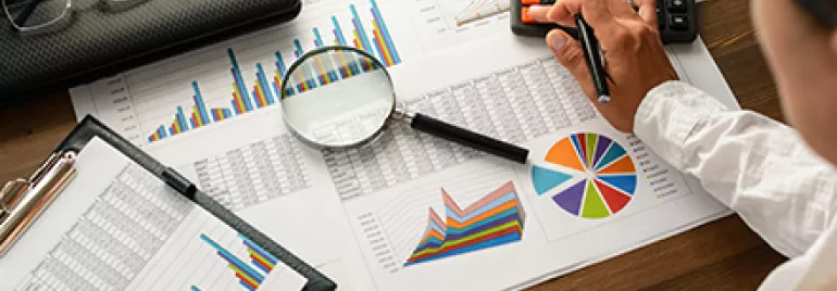 Travail sur des graphiques et calculs financiers sur un bureau en bois.