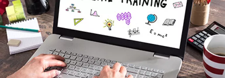 Personne tapant sur un ordinateur portable avec 'Online Training' à l'écran.