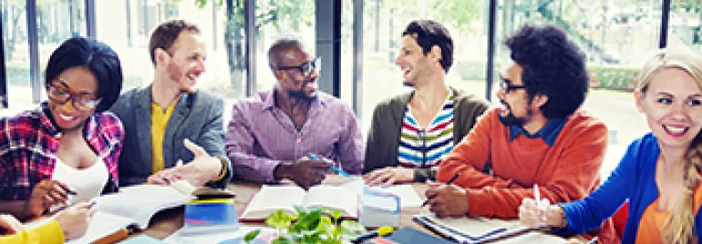 Groupe de personnes souriantes travaillant autour d'une table.