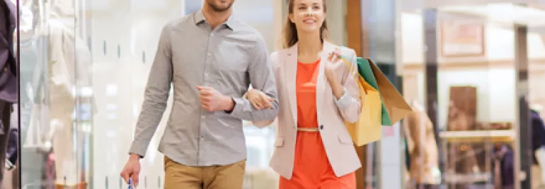 Deux personnes marchant dans un centre commercial avec des sacs à provisions.