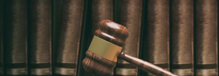 Marteau de juge en bois devant des livres de droit.