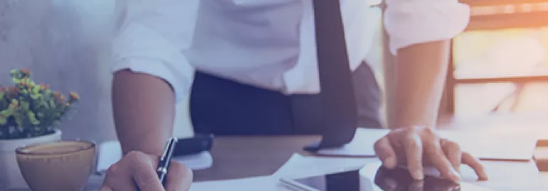 Personne travaillant sur des rapports avec une tablette et un café sur le bureau.