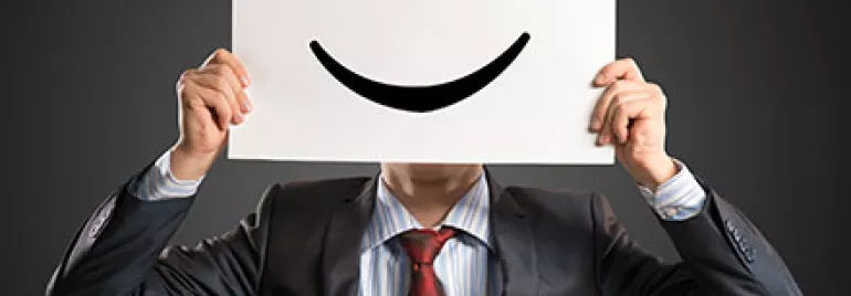 Une personne tient un panneau avec un visage souriant dessiné dessus.