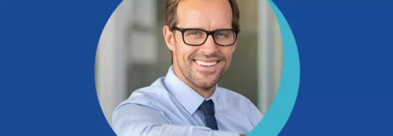 Personne souriante portant des lunettes et une chemise bleue.