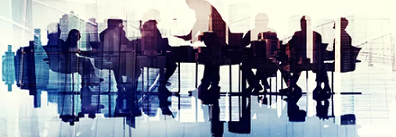 Silhouettes de personnes en réunion autour d'une table.