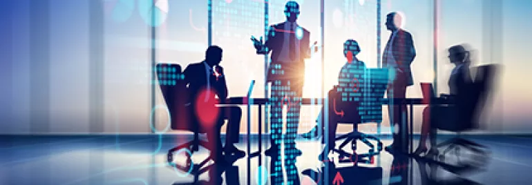 Réunion de professionnels discutant devant un écran numérique.