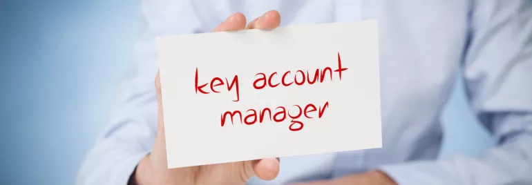 Une main tient une carte avec le texte 'key account manager'.