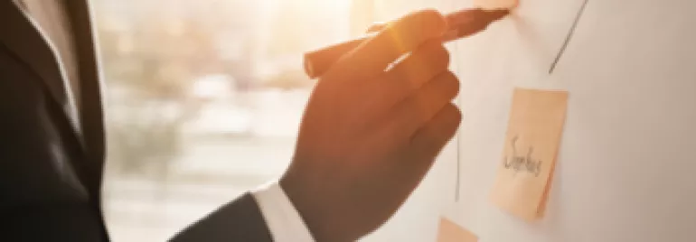 Personne écrivant sur un tableau avec des post-it.