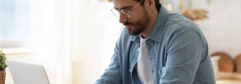 Personne travaillant sur un ordinateur portable dans une cuisine lumineuse.