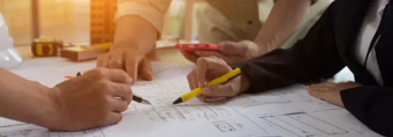 Groupe de personnes travaillant sur des plans sur une table.