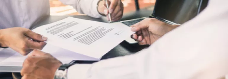 Deux personnes signent un document sur une table.