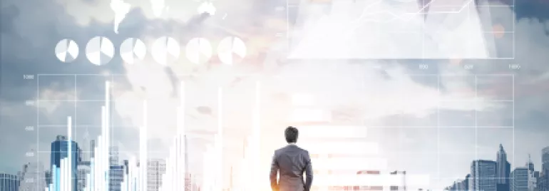Une personne debout devant des graphiques financiers et un horizon urbain.