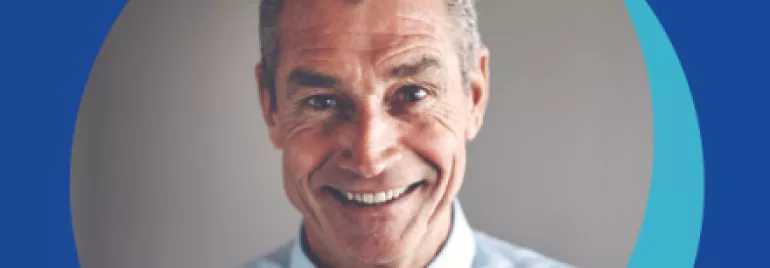 Personne souriante en chemise bleue et cravate à pois.