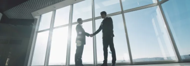 Deux personnes se serrant la main dans un bureau lumineux.