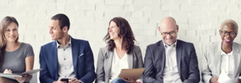 Groupe de personnes assises sur des chaises, souriantes.