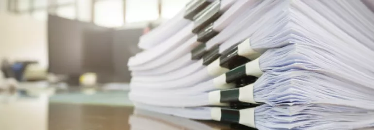 Pile de documents empilés sur une table en bois.