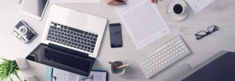 Bureau avec ordinateur, tablette et café, vue de dessus.