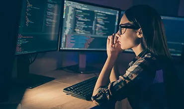 Personne concentrée sur des écrans d'ordinateur avec du code.