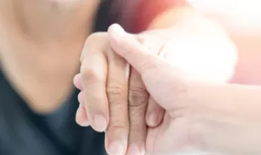Une main tient une autre en geste de soutien.