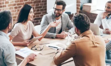 Groupe de personnes discutant autour d'une table en réunion.