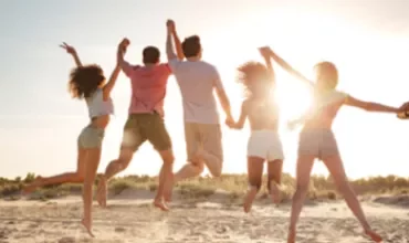 Un groupe de personnes sautant joyeusement sur la plage au coucher du soleil.