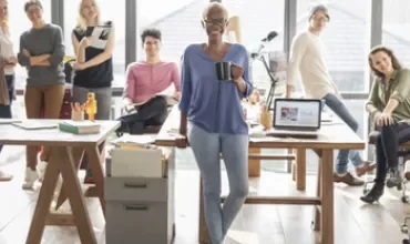 Groupe de personnes dans un bureau moderne, une personne au centre tenant une tasse.