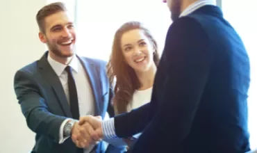 Gens en réunion se serrant la main, souriants.