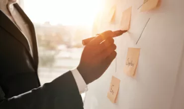 Personne écrivant sur un tableau avec des notes adhésives.