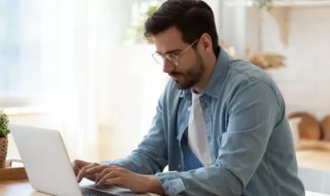 Personne utilisant un ordinateur portable à une table en bois.