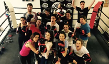 Groupe de boxeurs souriants posant dans un ring de boxe.