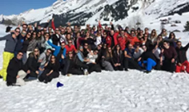 Groupe de personnes sur la neige avec des montagnes en arrière-plan.