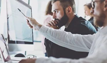 Personnes travaillant ensemble devant un écran d'ordinateur.
