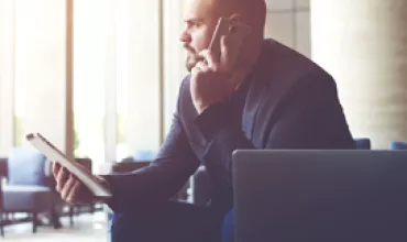 Personne assise utilisant un téléphone et une tablette.