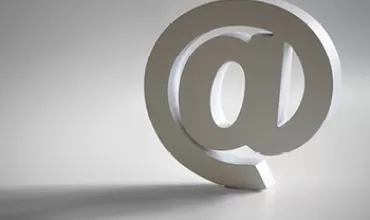 Symbole 3D de l'arobase sur fond gris.
