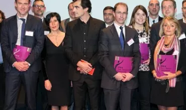 Groupe de personnes tenant des dossiers violets posant ensemble lors d'un événement.