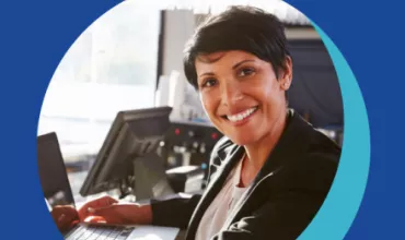Personne souriante travaillant à un bureau avec un ordinateur portable.