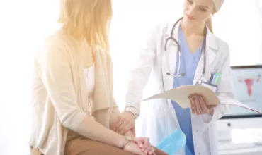 Un médecin discute avec un patient tout en tenant un dossier.