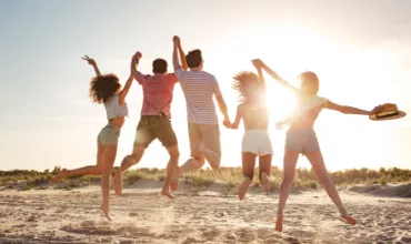 Des amis sautant sur la plage au coucher du soleil.