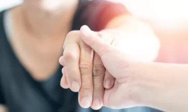 Deux personnes se tiennent la main avec compassion.