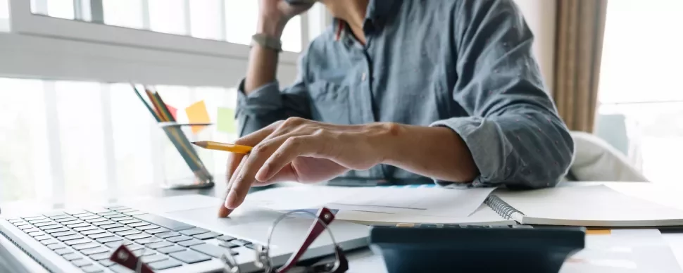 Personne travaillant sur un ordinateur portable avec des documents ouverts.